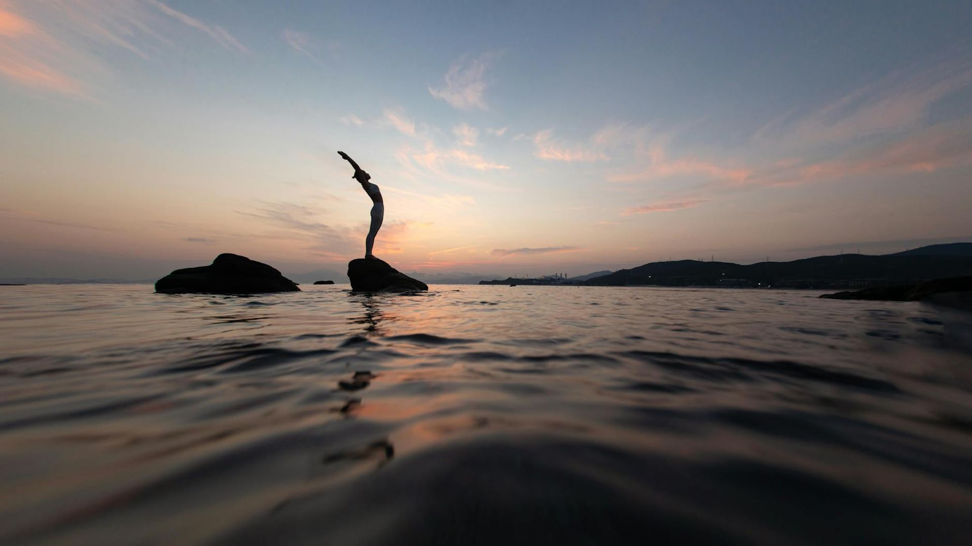 Silhouette of a person in a serene yoga pose at dusk.